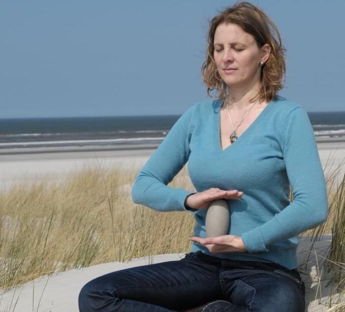 Nina meditiert mit einem Gefäß Wasserkefir am Strand